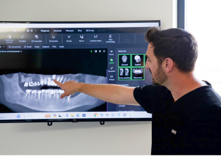 Doctor pointing at model of teeth on TV